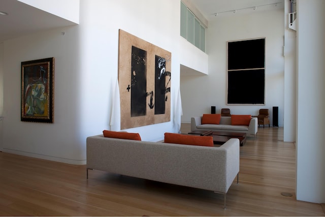 living room with rail lighting, a towering ceiling, and light wood-style floors