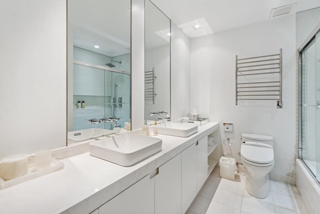 641 5th Ave Unit 27C, New York City, NY 10022 - full bath featuring radiator, toilet, a towel warming rack, double vanity, and tile patterned floors