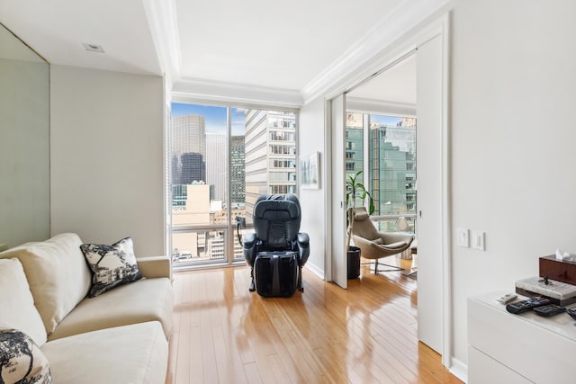 641 5th Ave Unit 27C, New York City, NY 10022 - living area with floor to ceiling windows, light wood-style floors, crown molding, a city view, and baseboards