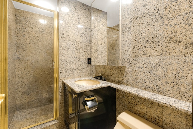 bathroom with a shower with door, vanity, and tile walls