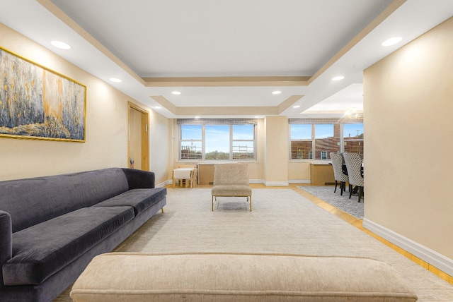 living area featuring a tray ceiling, light wood finished floors, baseboards, and recessed lighting