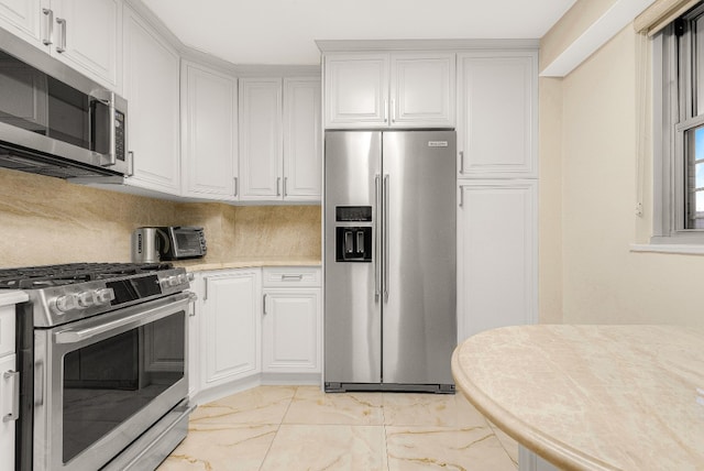 kitchen with tasteful backsplash, appliances with stainless steel finishes, and white cabinets