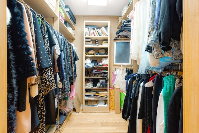 walk in closet with light hardwood / wood-style floors