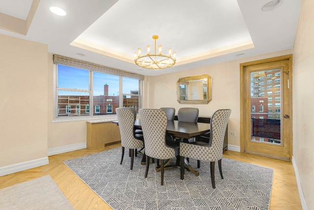 dining space with an inviting chandelier and a raised ceiling