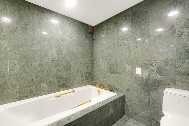 bathroom with toilet, tile walls, and a bath