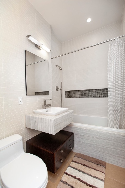 243 W 60th St Unit 3A, New York City, NY 10023 - full bathroom featuring tiled shower / bath, tile walls, toilet, tile patterned floors, and vanity