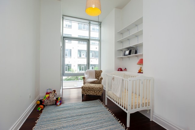 bedroom featuring dark wood-type flooring, multiple windows, and a nursery area