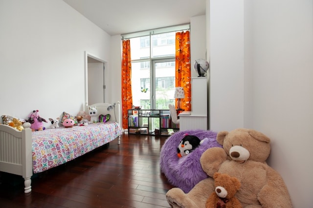 bedroom with multiple windows, a wall of windows, and dark hardwood / wood-style flooring