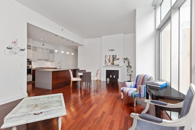 living room featuring a wealth of natural light, dark wood-style flooring, a fireplace, and baseboards