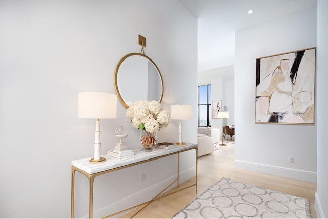 hall featuring light wood-style flooring and baseboards