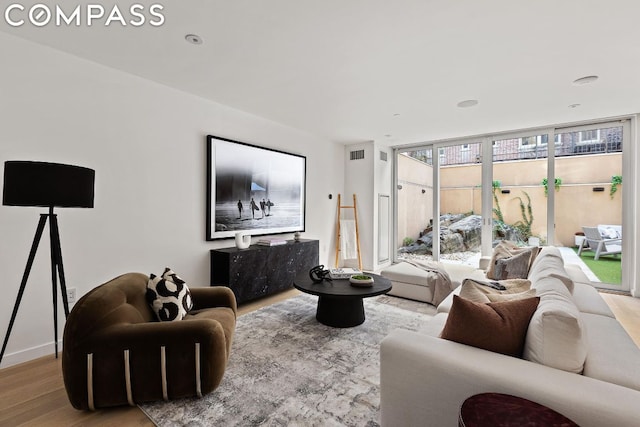 living room with floor to ceiling windows and light hardwood / wood-style flooring