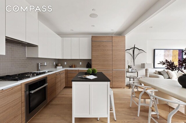 kitchen with backsplash, white cabinets, a center island, and appliances with stainless steel finishes