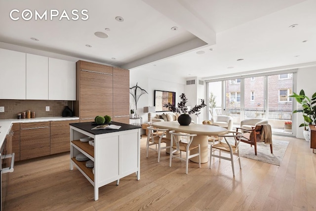 kitchen with floor to ceiling windows, a center island, light hardwood / wood-style flooring, decorative backsplash, and white cabinets