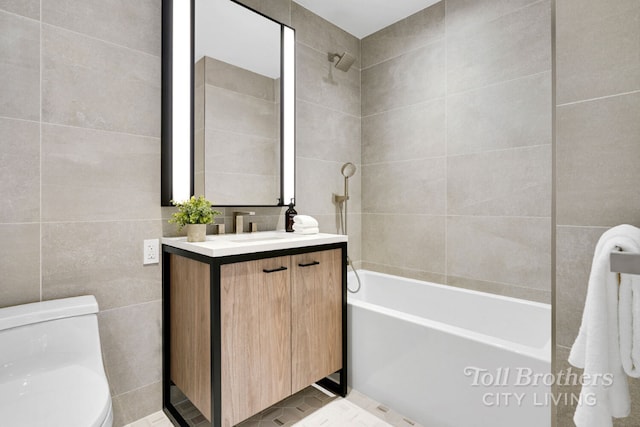 full bathroom featuring toilet, tiled shower / bath, tile walls, and vanity