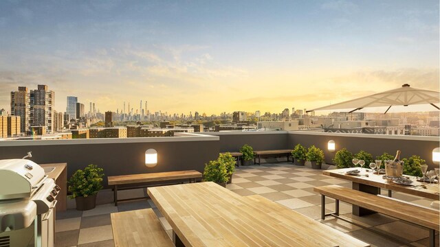 patio terrace at dusk featuring grilling area and a balcony