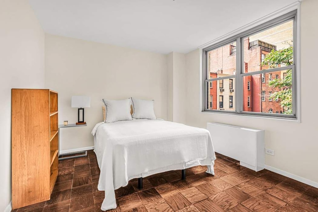 bedroom featuring multiple windows and radiator heating unit