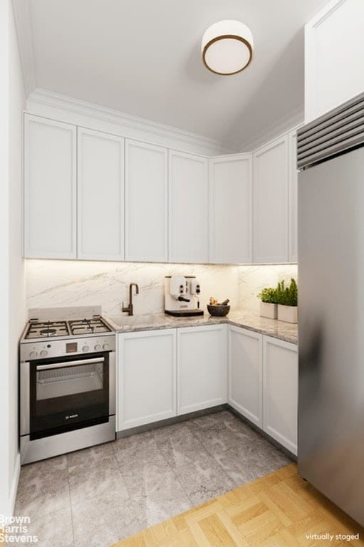 kitchen featuring appliances with stainless steel finishes, sink, white cabinets, decorative backsplash, and light stone countertops