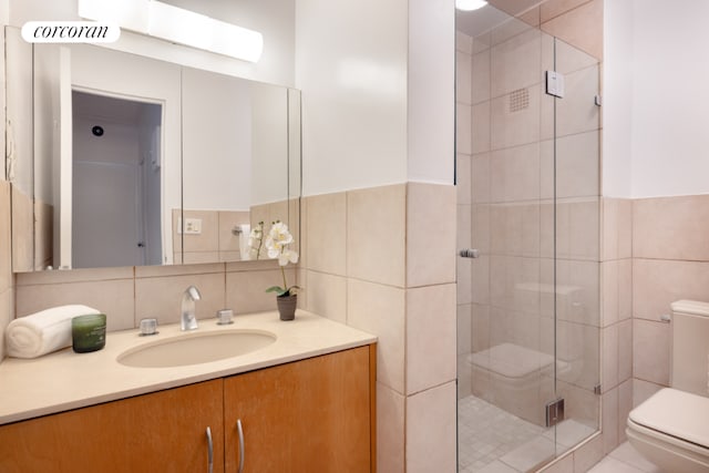 bathroom with toilet, vanity, tile walls, and an enclosed shower