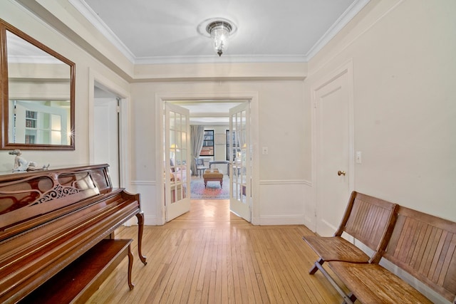 hallway with light wood-type flooring, baseboards, ornamental molding, and french doors