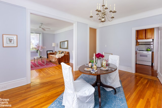 dining space with hardwood / wood-style flooring and ceiling fan with notable chandelier