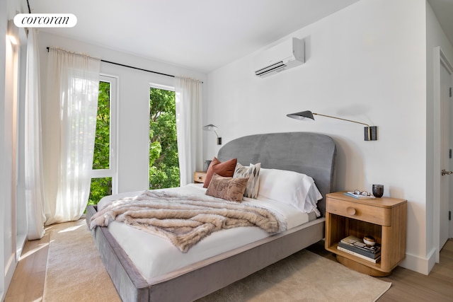 bedroom featuring wood finished floors and an AC wall unit