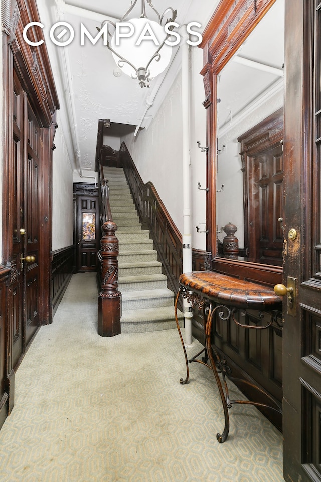 entrance foyer featuring wainscoting, stairway, and carpet flooring