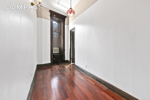 spare room with radiator, baseboards, and dark wood-type flooring