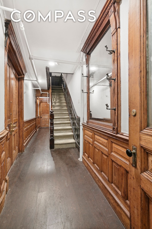 hall featuring dark wood-style floors, wainscoting, and stairs