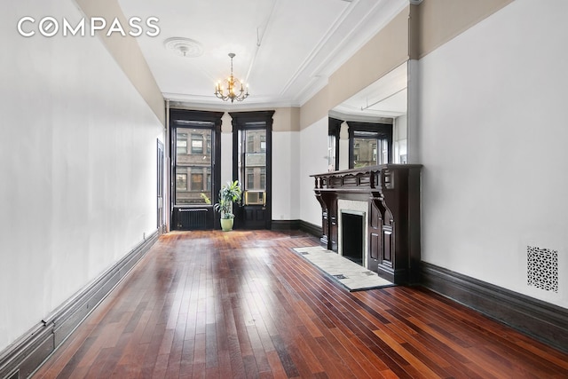 entryway featuring baseboards, radiator, hardwood / wood-style flooring, a fireplace, and a chandelier