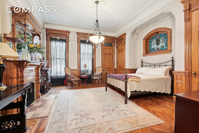 bedroom featuring a wainscoted wall, ornamental molding, radiator heating unit, and a fireplace