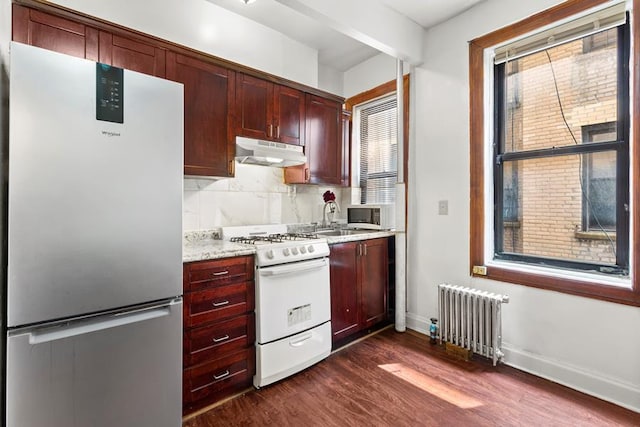 kitchen featuring dark wood-style flooring, white gas range, radiator, freestanding refrigerator, and under cabinet range hood