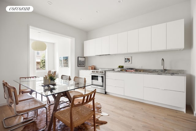 kitchen with sink, white cabinets, light hardwood / wood-style flooring, and stainless steel range with electric stovetop