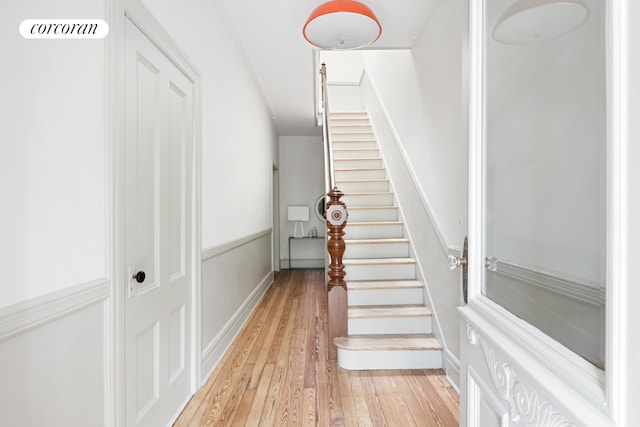 staircase with hardwood / wood-style flooring and ornamental molding