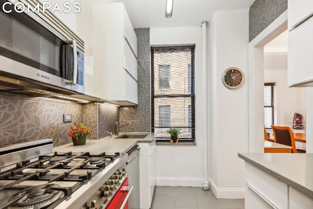 kitchen with decorative backsplash, sink, stainless steel appliances, and white cabinetry