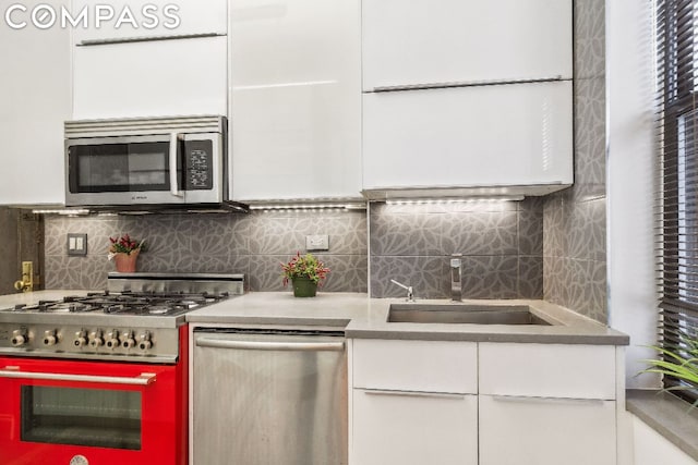 kitchen with tasteful backsplash, appliances with stainless steel finishes, sink, and white cabinetry