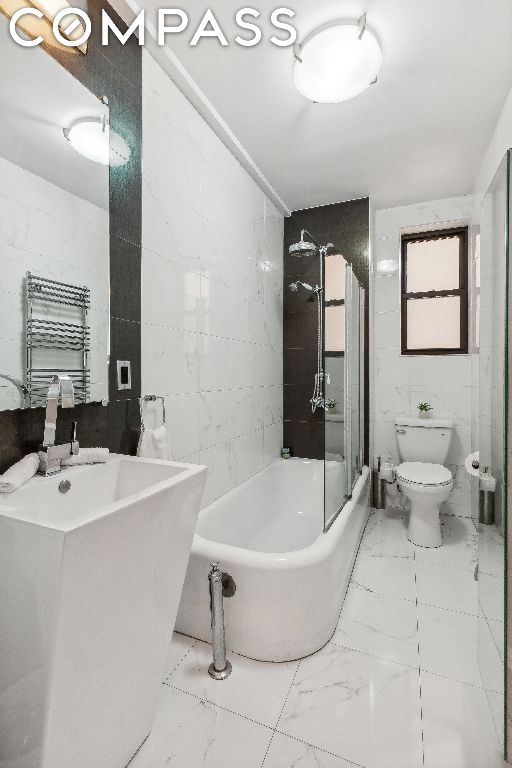 bathroom featuring tile walls, toilet, and radiator