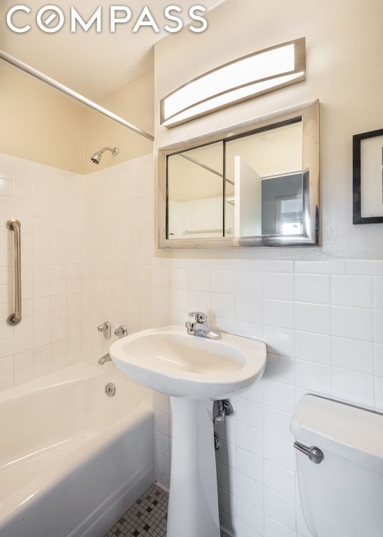 bathroom with tile walls, toilet, tiled shower / bath, and tile patterned flooring