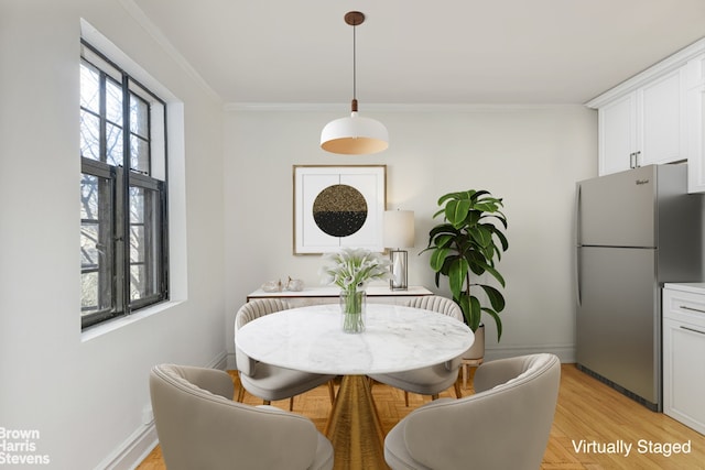 dining area featuring light wood-type flooring and ornamental molding