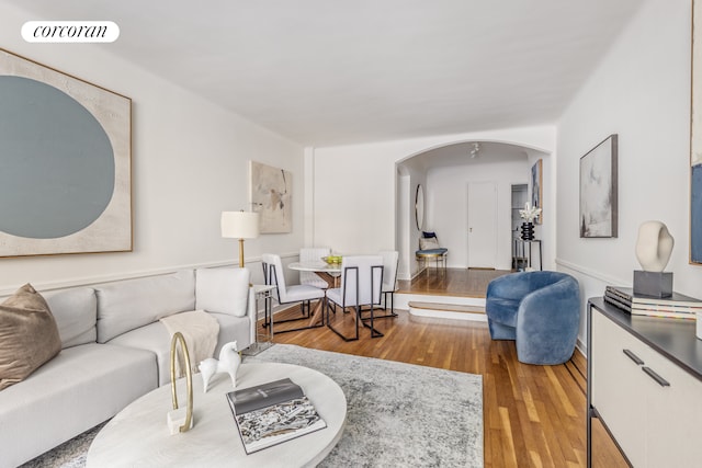 living area featuring arched walkways, wood finished floors, and visible vents