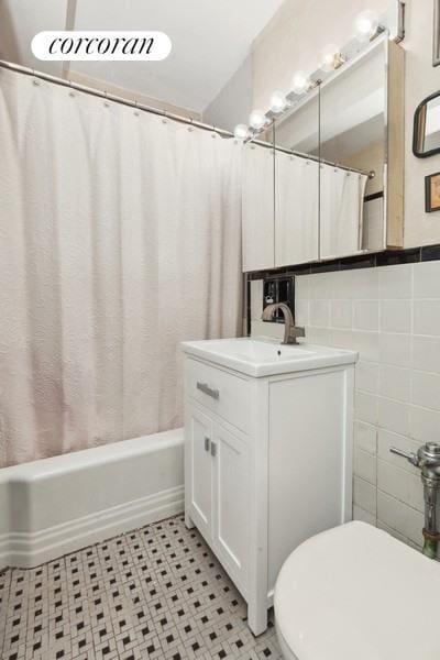 full bathroom featuring vanity, tile walls, shower / tub combo, and toilet