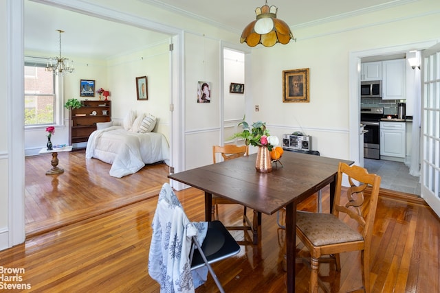 dining area featuring light wood-type flooring, a notable chandelier, and crown molding