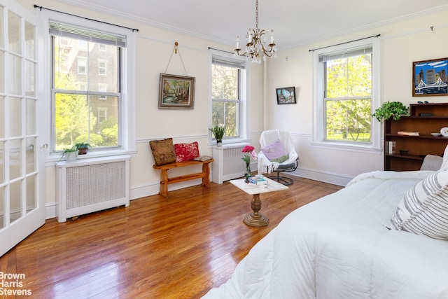 bedroom with ornamental molding, radiator, multiple windows, and wood finished floors