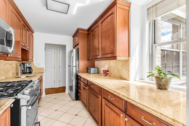 kitchen featuring tasteful backsplash, stainless steel appliances, light stone countertops, and sink