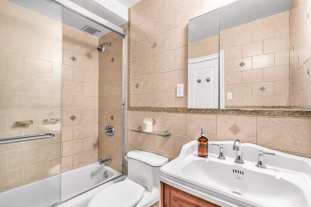 full bathroom with toilet, vanity, bath / shower combo with glass door, and tile walls