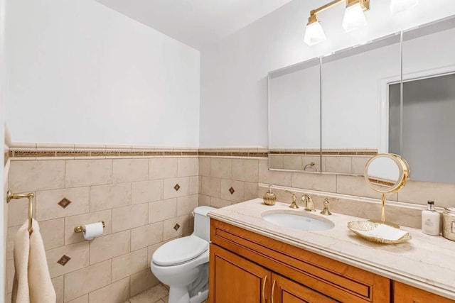 bathroom featuring vanity, toilet, and tile walls