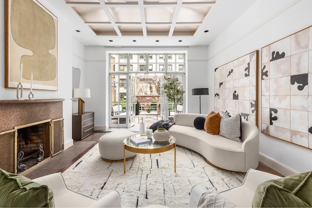 living area with baseboards, a high ceiling, a fireplace, and coffered ceiling