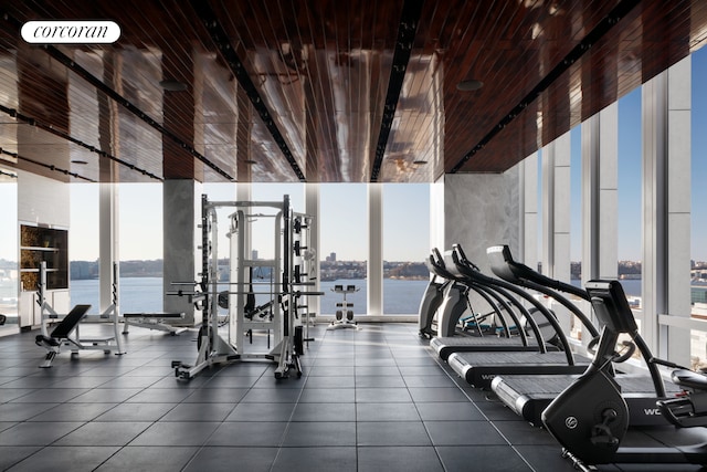 exercise room with a wall of windows, plenty of natural light, and a water view