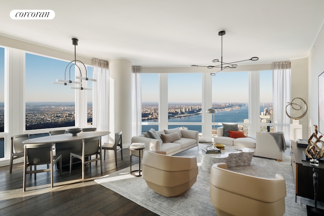 living area featuring a chandelier, dark wood-style flooring, a water view, and plenty of natural light