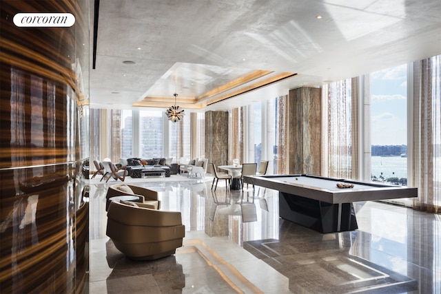 game room with plenty of natural light, a chandelier, a tray ceiling, billiards table, and floor to ceiling windows