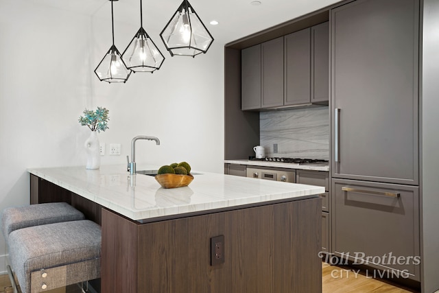218 W 103rd St Unit 4B, New York City, NY 10025 - kitchen with tasteful backsplash, light stone countertops, a kitchen bar, a peninsula, and stainless steel gas stovetop
